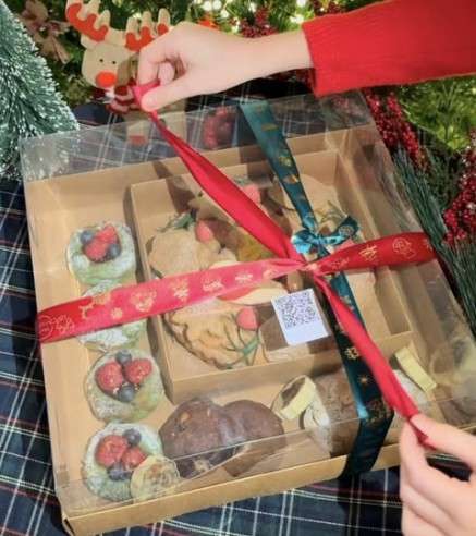 Hands tying a red ribbon around a gift box